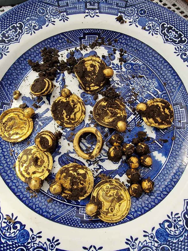 Trois anneaux en or, neuf pendentifs en or (bractéates), en forme de pièces de monnaie, dix perles en or, le tout mis au jour sur l'île de Rennesøy en Norvège, vieux de 1500 ans.